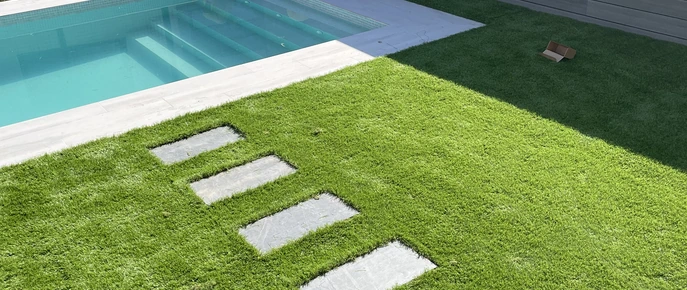 Losetas de paso sobre césped junto a una piscina