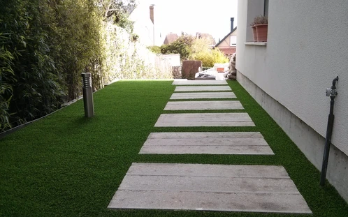 Sendero de losetas grandes entre césped junto a una vivienda