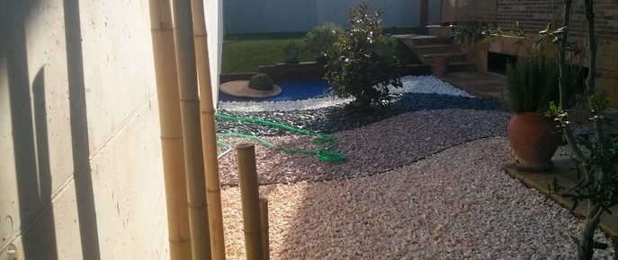 Zona de áridos decorativos con plantas junto a una entrada
