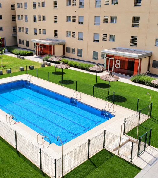 Césped artificial junto a una piscina comunitaria rodeada de edificios