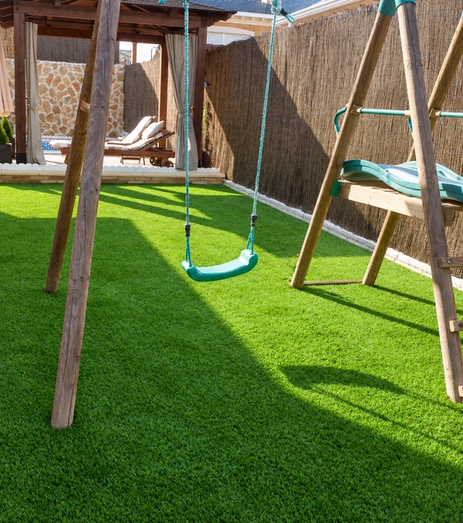 Columpios de madera sobre césped artificial en una zona infantil
