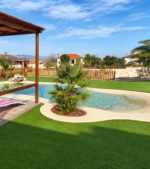 Jardín con césped artificial y una piscina de formas curvas