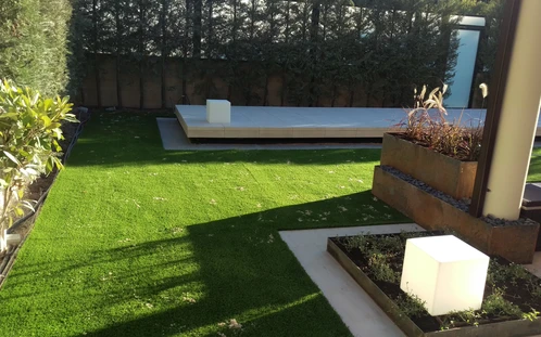 Jardín con césped, jardinera y superficies a distinta altura