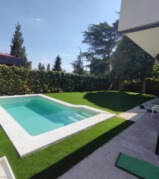 Jardín con césped artificial alrededor de una piscina