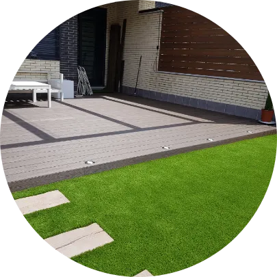 Terraza con césped artificial y pasarela de losas junto a una vivienda